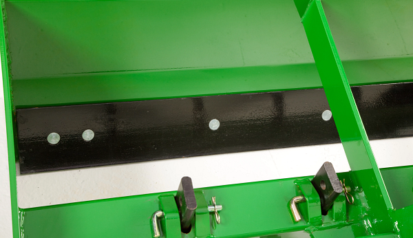 Close-up of agricultural implement showing adjustable mounting brackets with locking pins and clips beneath a black wear strip.