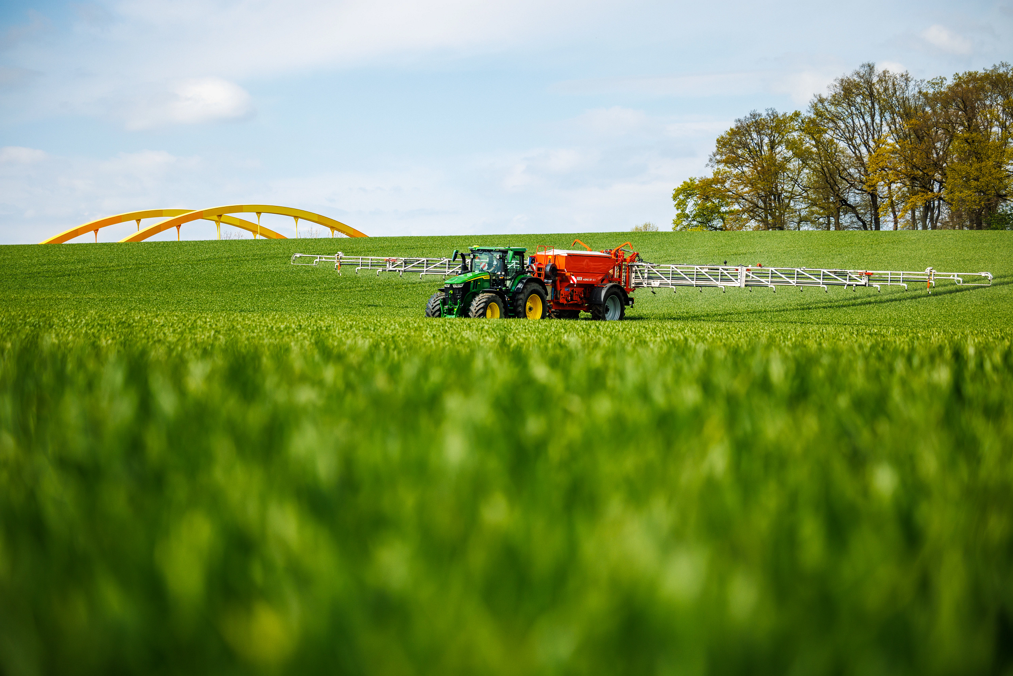 7R 350 Tractor pulls a fertilizer spreader through a field