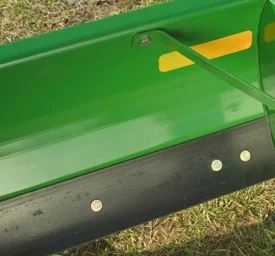 Close-up of a rear blade's black reversible cutting edge on green blade