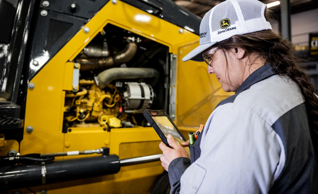 Service tech checks a tablet next to a JD4G engine