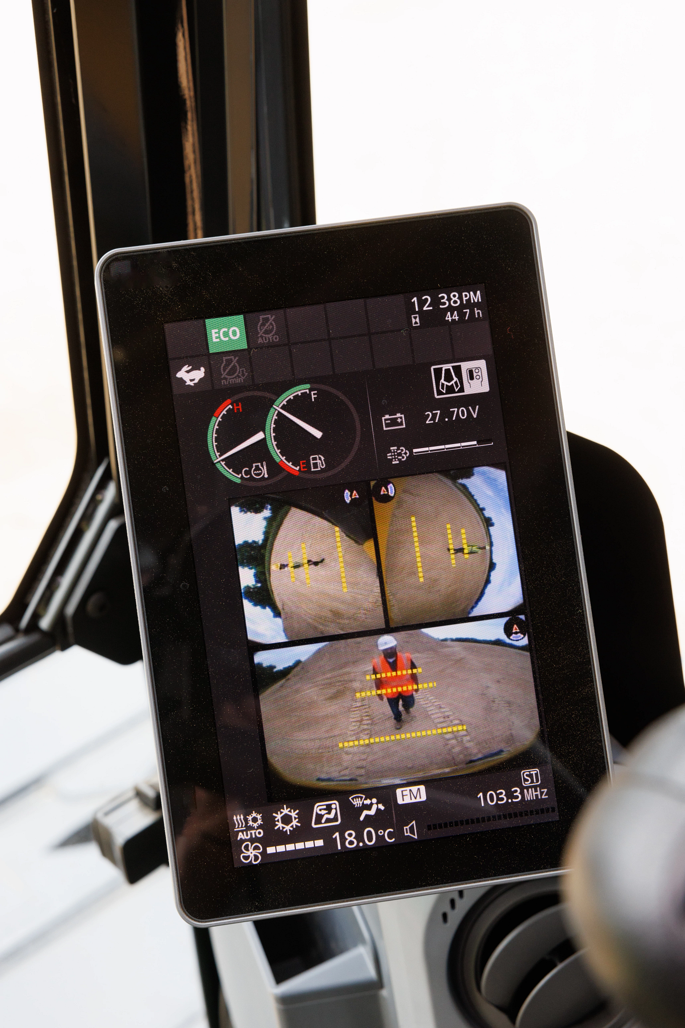 Close-up of an in-cab display screen showing multiple camera views and machine data, including speed, temperature, and rearview guidance lines