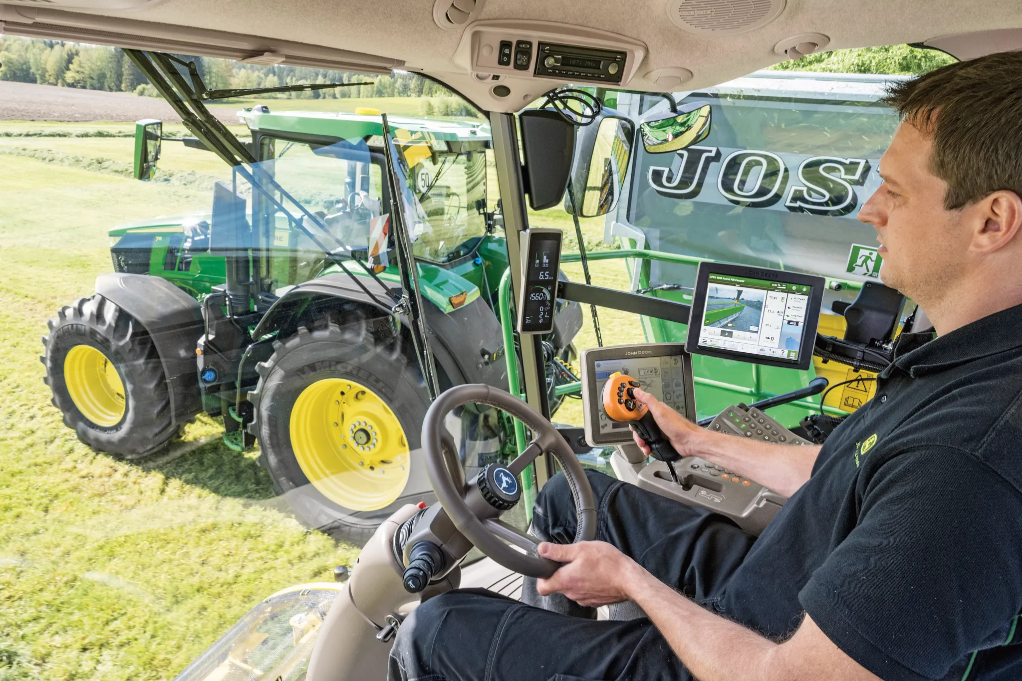 Man in cab operates steering wheel and multifunction lever in field