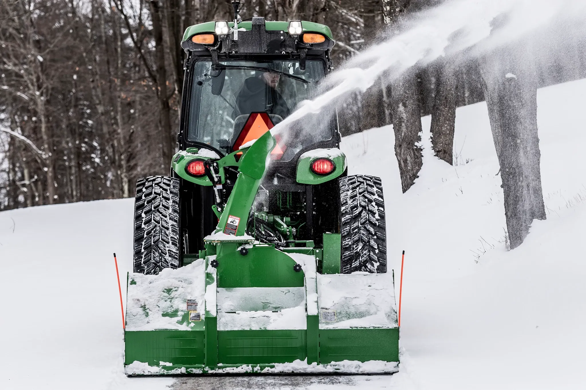Blowing snow using a SB1174 Snowblower on 4075R Tractor along a tree line