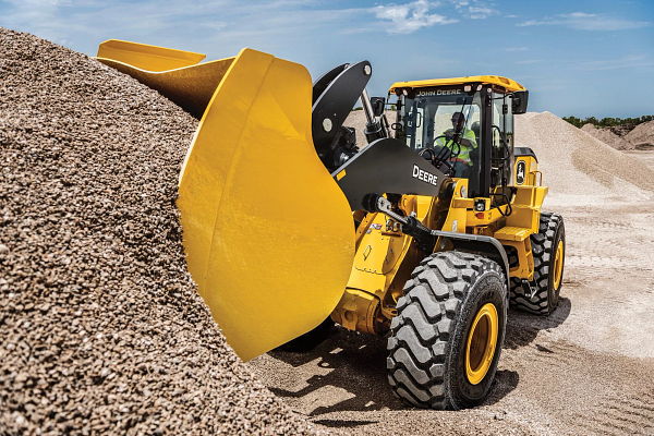 644 G-Tier wheel loader lifting a wide bucket into a large pile of gravel at a construction site.
