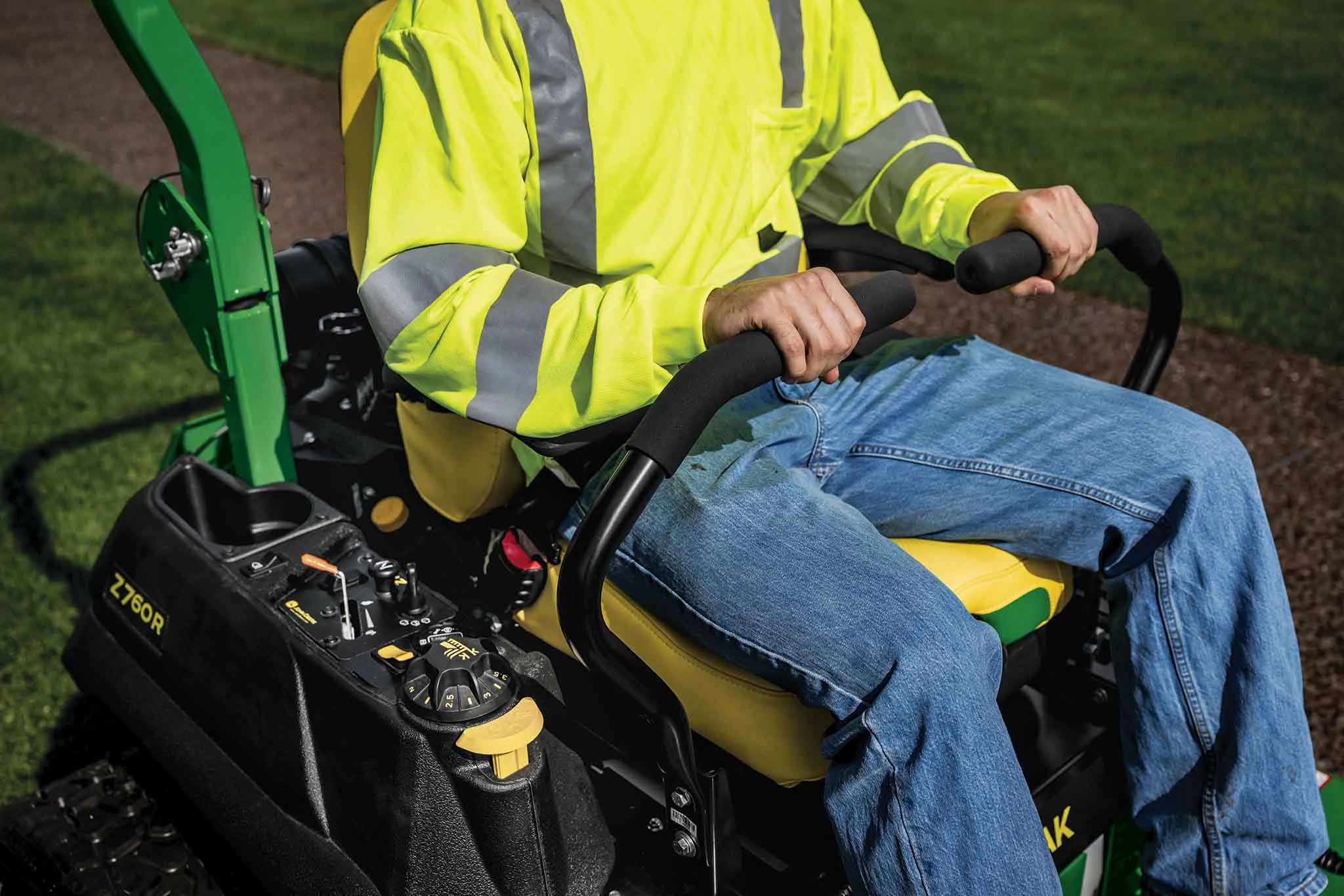 A zoomed-in shot of a landscaper operating a green Z760R zero-turn mower.