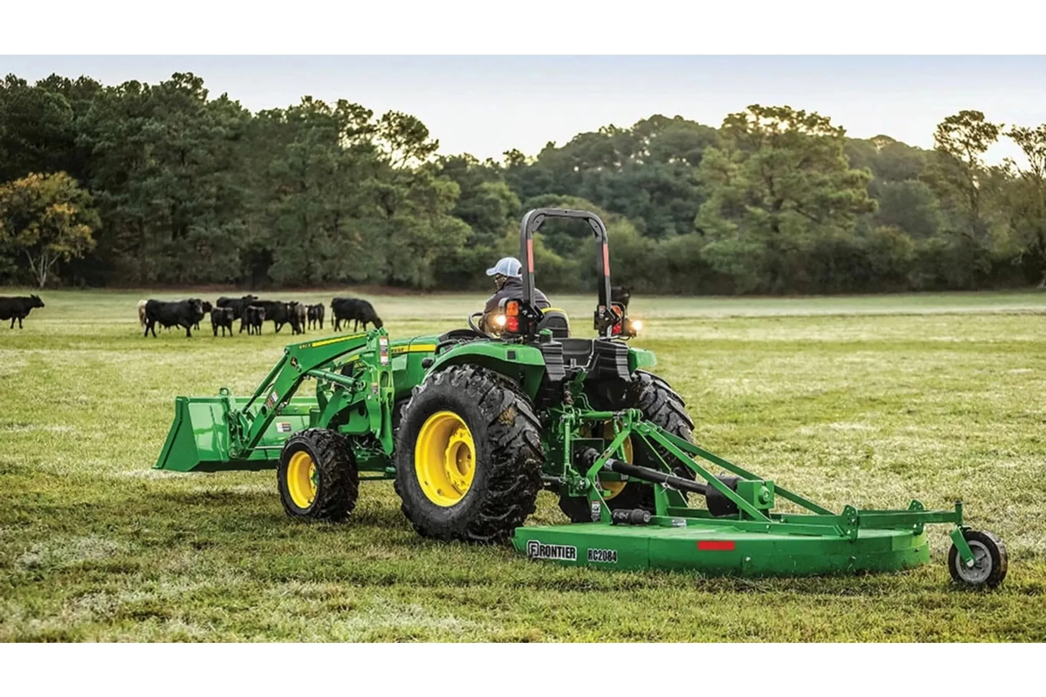 4066M Heavy Duty Compact Tractors with a farmer in a green tractor is standing in a field