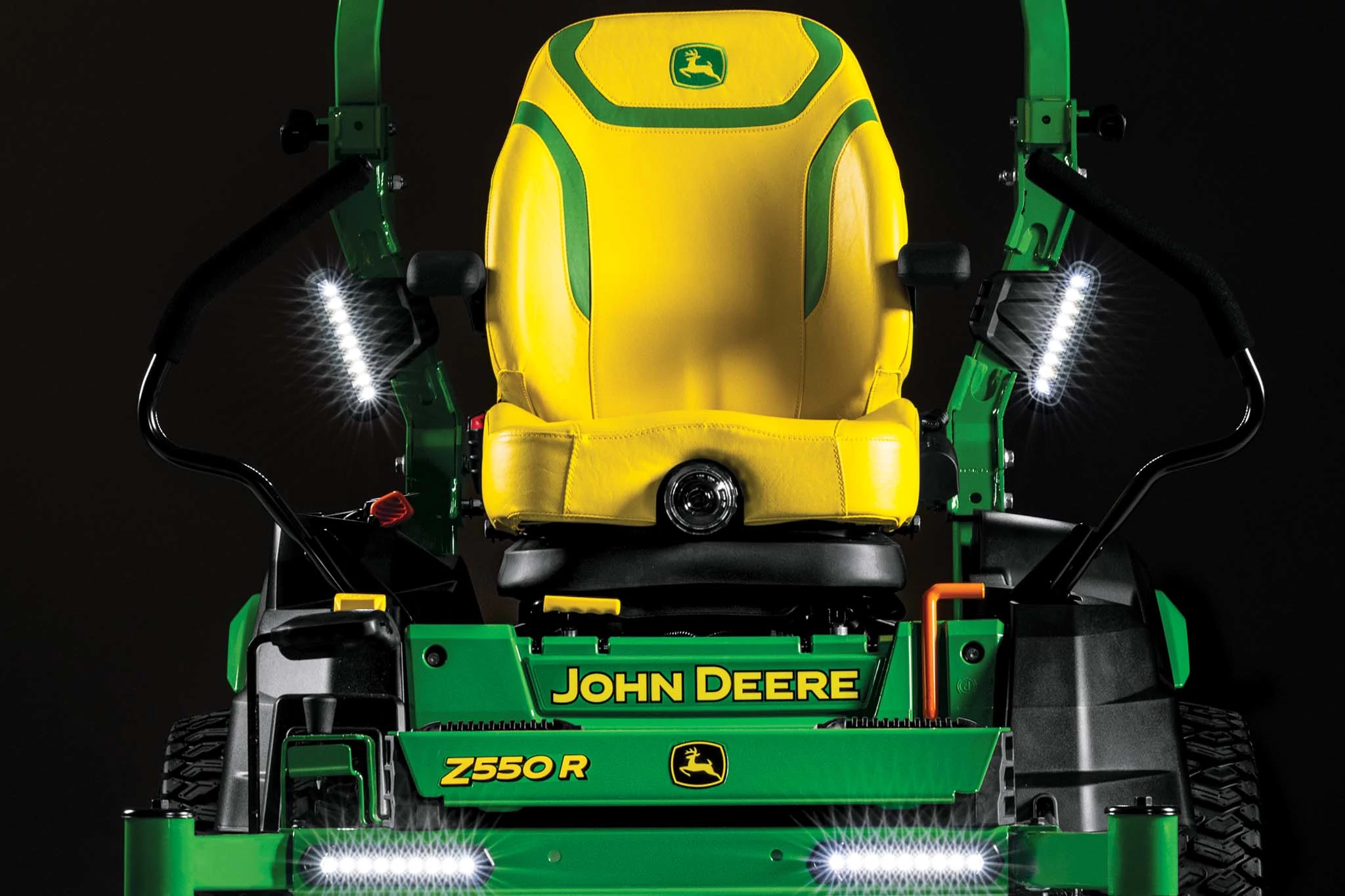 A dramatic close-up front shot of the yellow seat and LED lights on a Z550R zero-turn mower with a black background.