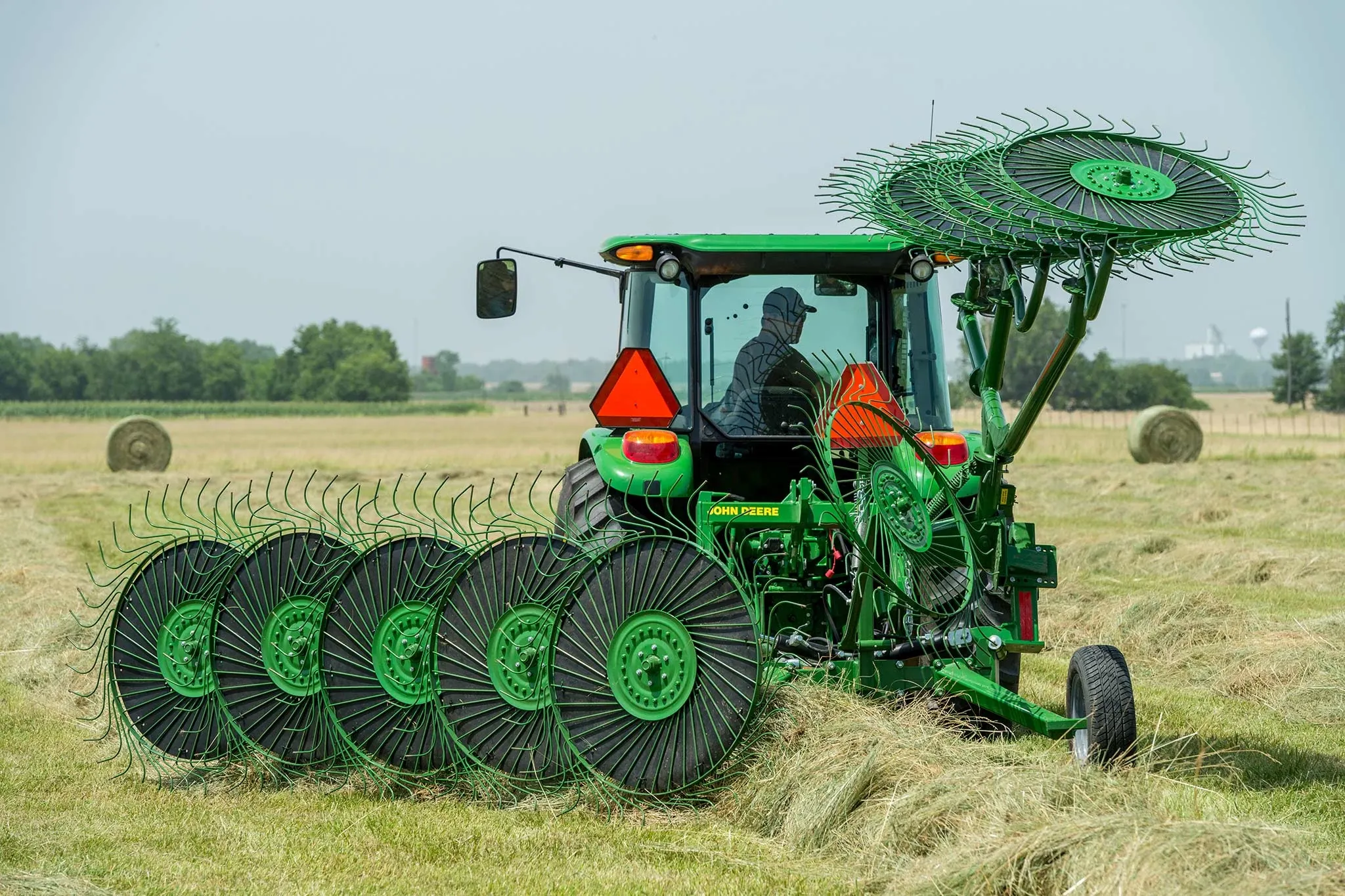 Rear view of a WR00 wheel rake at work behind a tractor in a hay field
