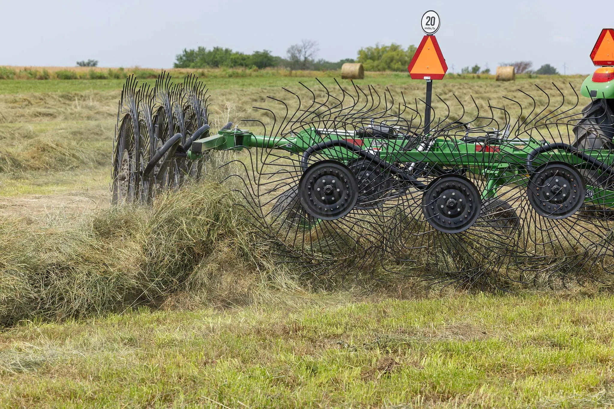 Rear right close-up of a WR3212 wheel rake at work on a pile of hay