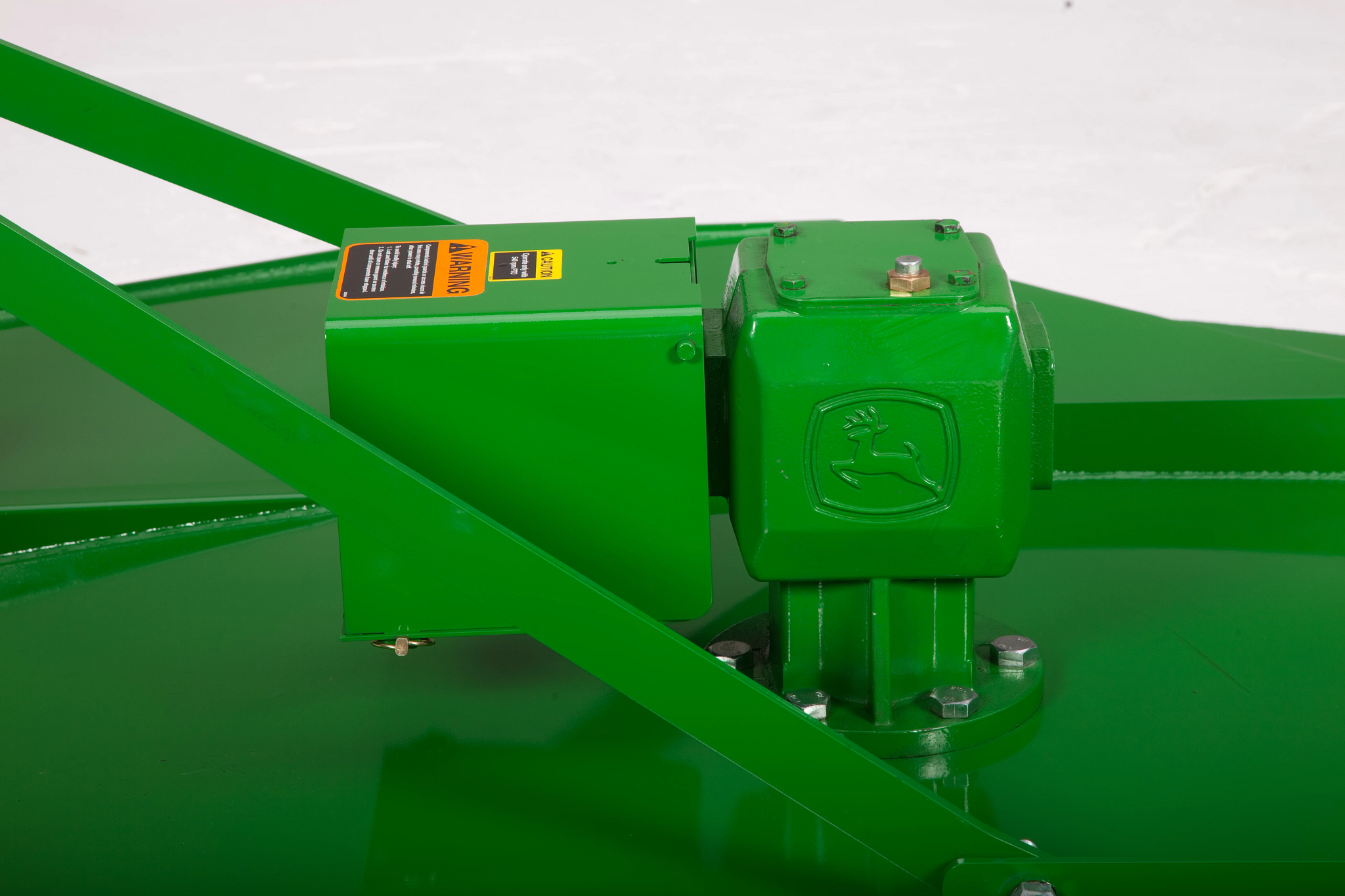 Close-up of a green gearcase mounted on a flat metal deck, with protective covers, mounting bolts, and support bars around it