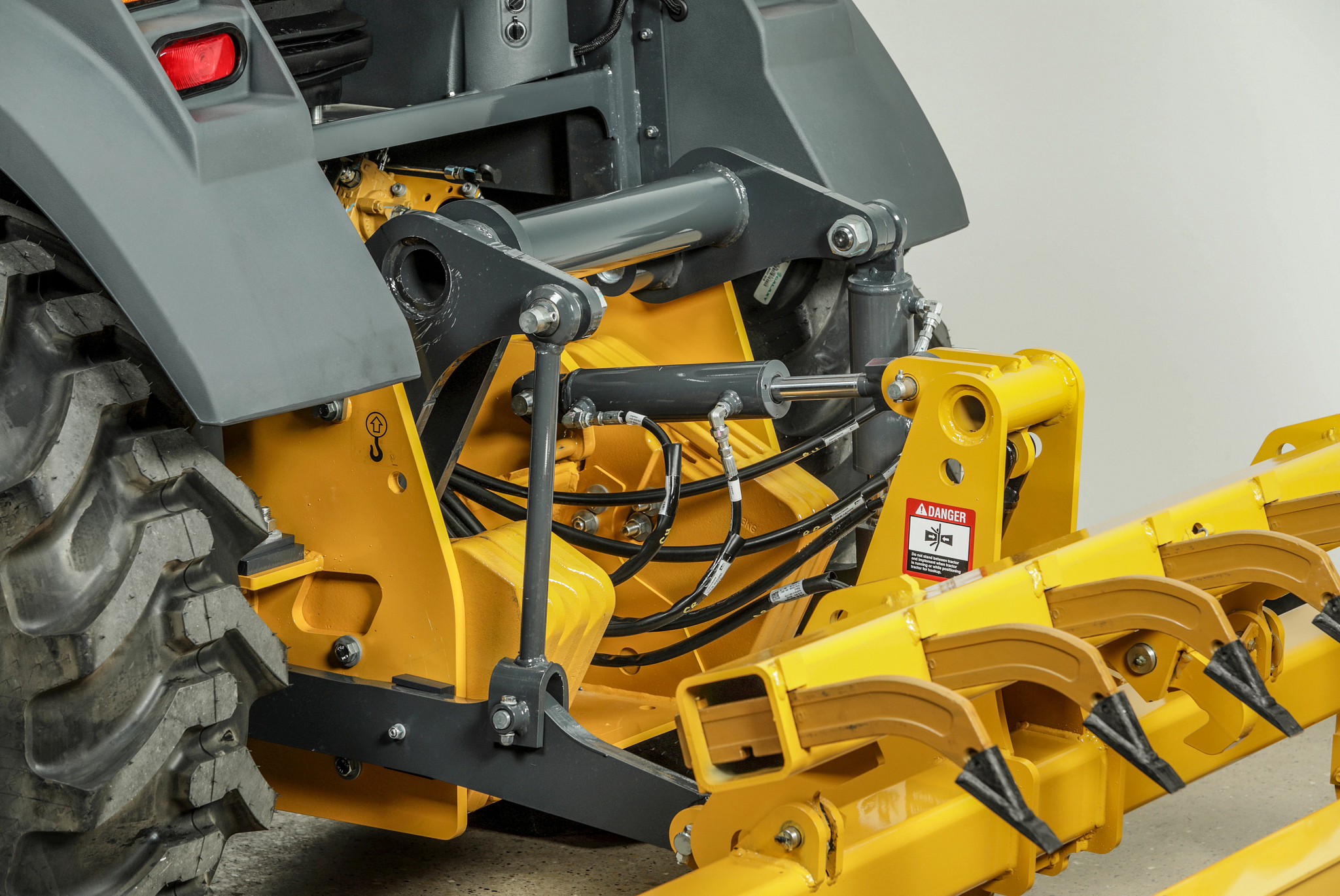 Rear left view of a 210G tractor loader's hydraulic implements between rear connection and attachment