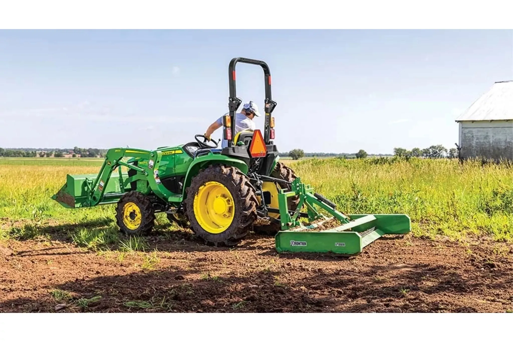 3025E 3 Series Compact Tractors with a farmer is driving a tractor with a plow attachment