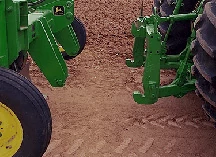Close-up of a 955 moldboard plow hitch and tractor connection about to meet over a dirt expanse