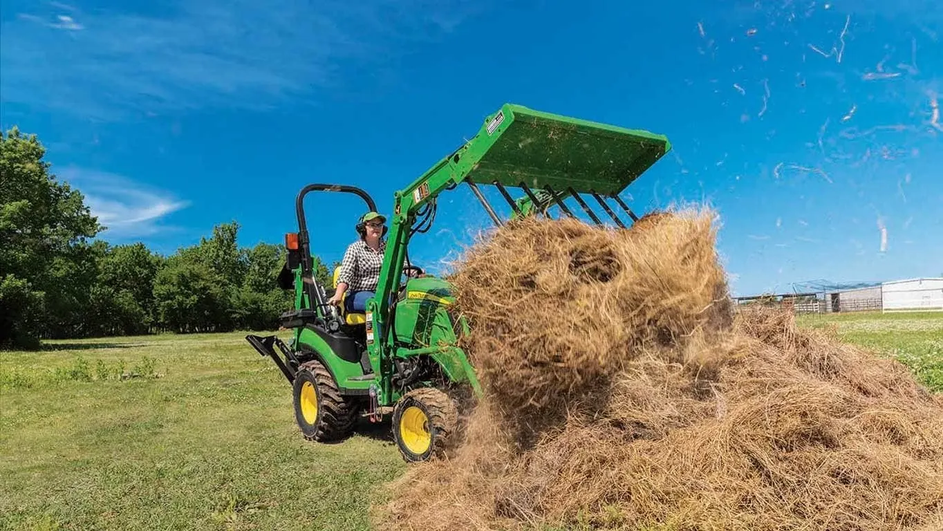 Front view of an AM20F Manure Fork moving hay in a pasture