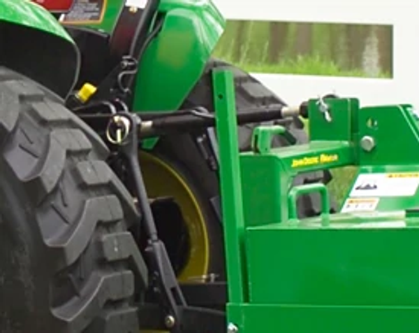 Close-up of the rear hitch and tires of a tractor with CA20 core aerator attached