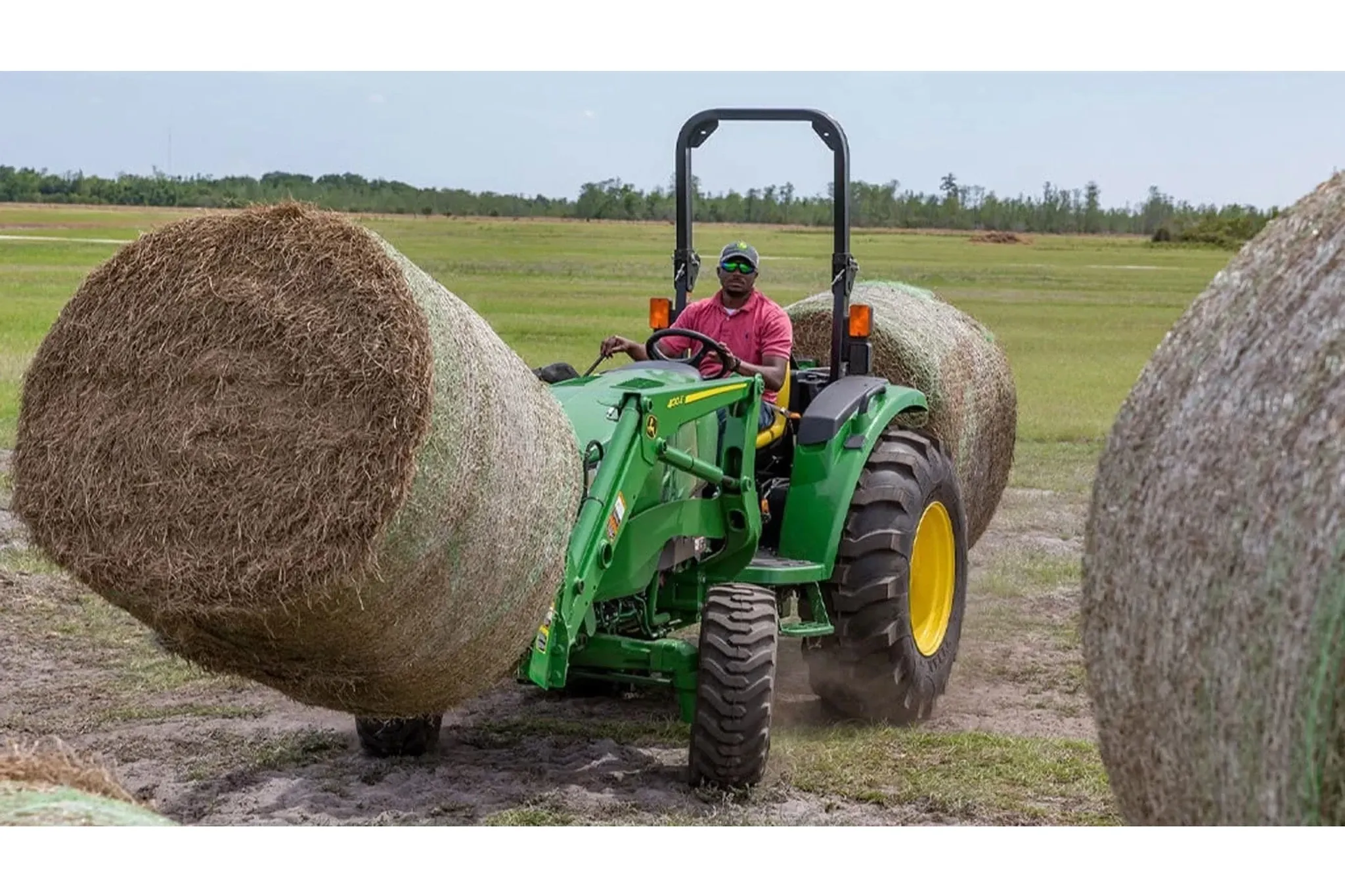 farmer operating a 4044M Compact Tractor to move hay bales