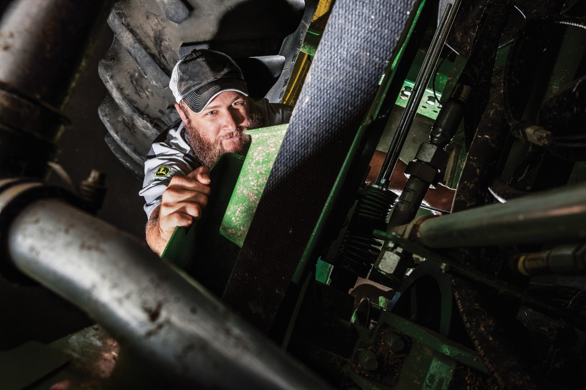 John Deere technician working beneath an S670 combine
