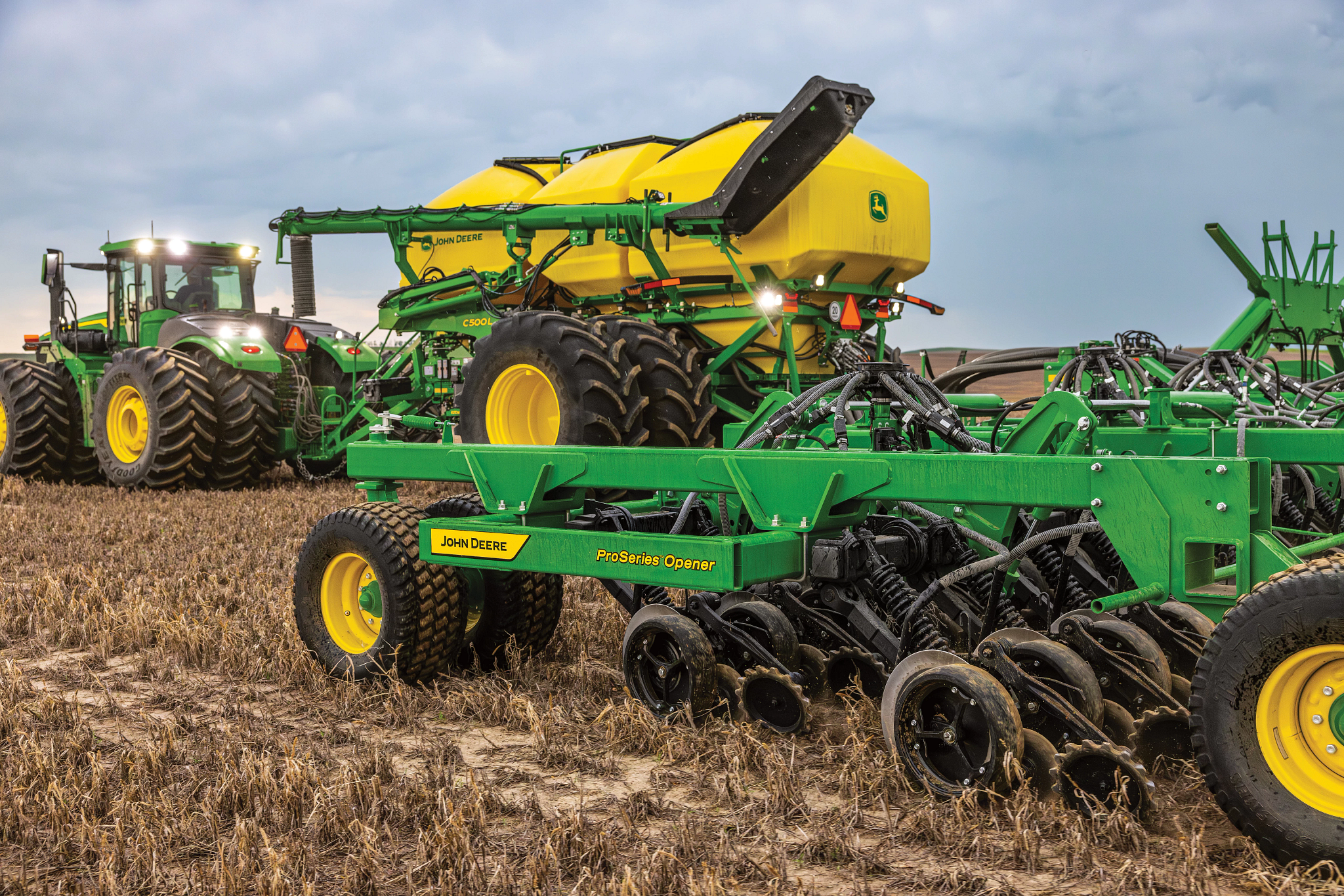 John Deere air seeder and tractor working ground in the field — Koenig Equipment