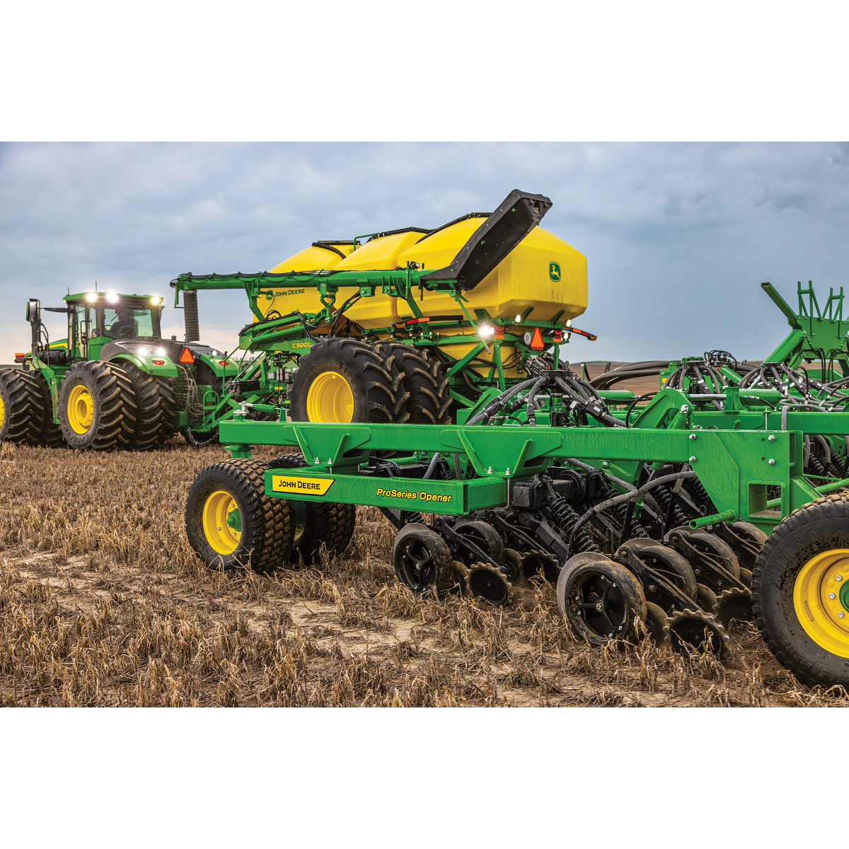 John Deere air seeder and tractor working ground in the field — Koenig Equipment