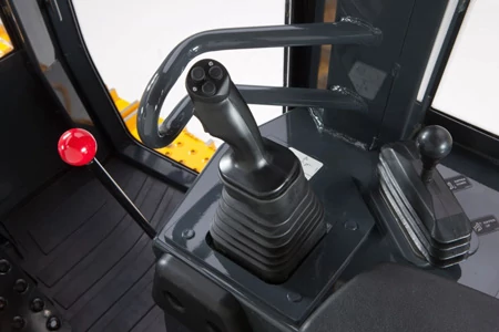 Close-up of a crawler loader cab showing a multi‑button joystick, a secondary control lever, and a red-handled lever mounted on a dark panel