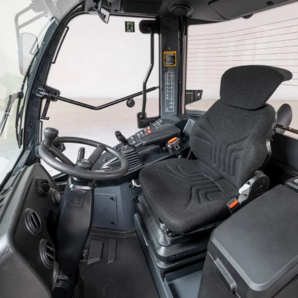 View of a G-Tier loader cab upon entering: black and gray dash, implements, and operator station