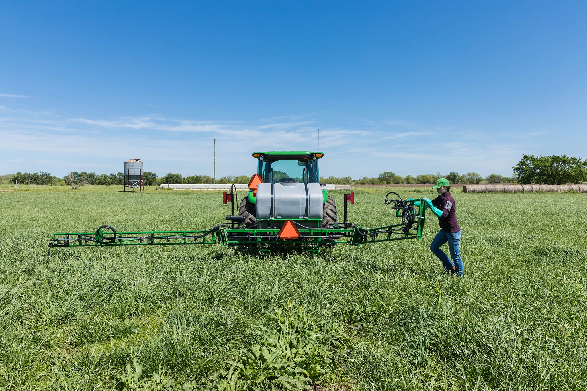 Field view of LS1130 Sprayer on 5075E Tractor with person working on the sprayer