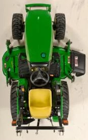 Top-down view of a awn tractor showing the hood, steering wheel, yellow operator seat, rear hitch assembly, and wide tires.
