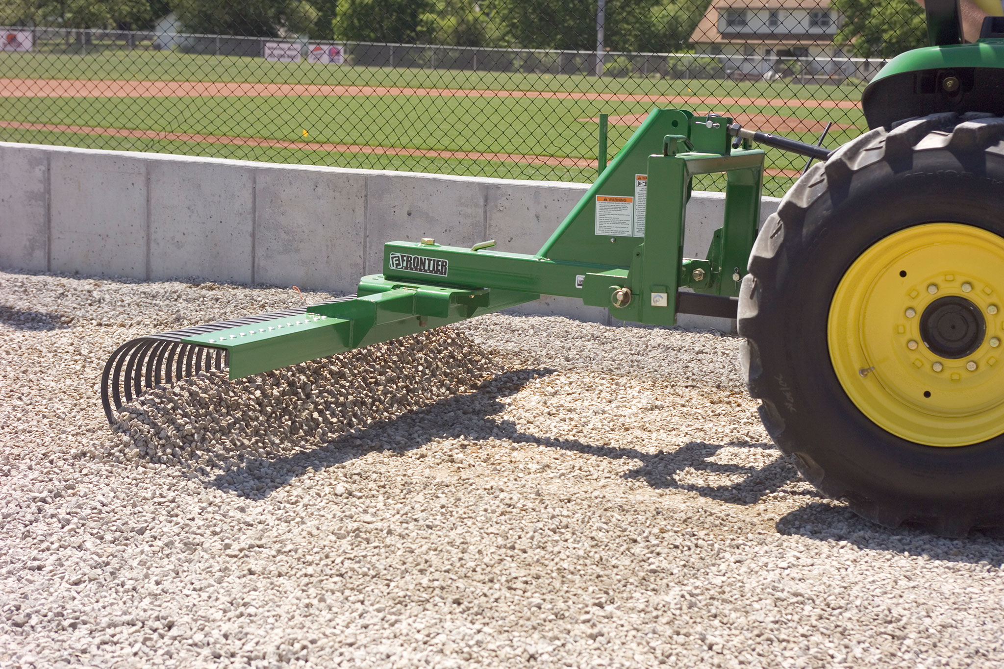 Right side view of steel frame on LR21 Landscape Rake raking gravel around the outside of a baseball field