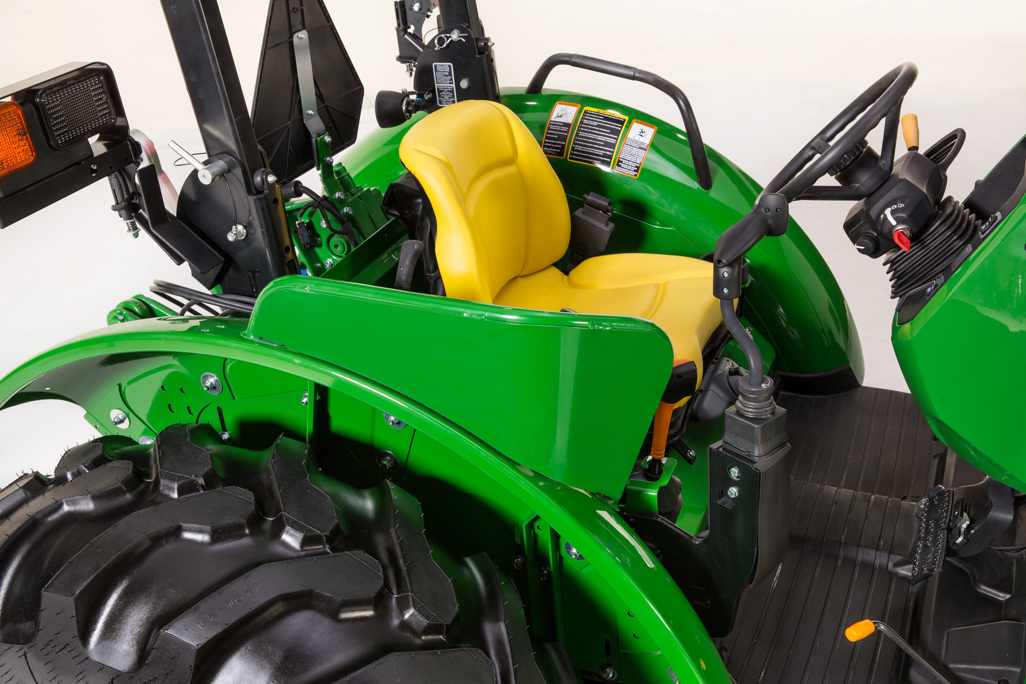Right side, angled close-up of a 5115ML tractor's Low-Profile Standard Open Operator Station (OOS) and top of right tire