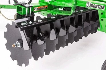 Studio close-up of one set of lined-up, notched disk blades on a green TM14D drawn disk harrow