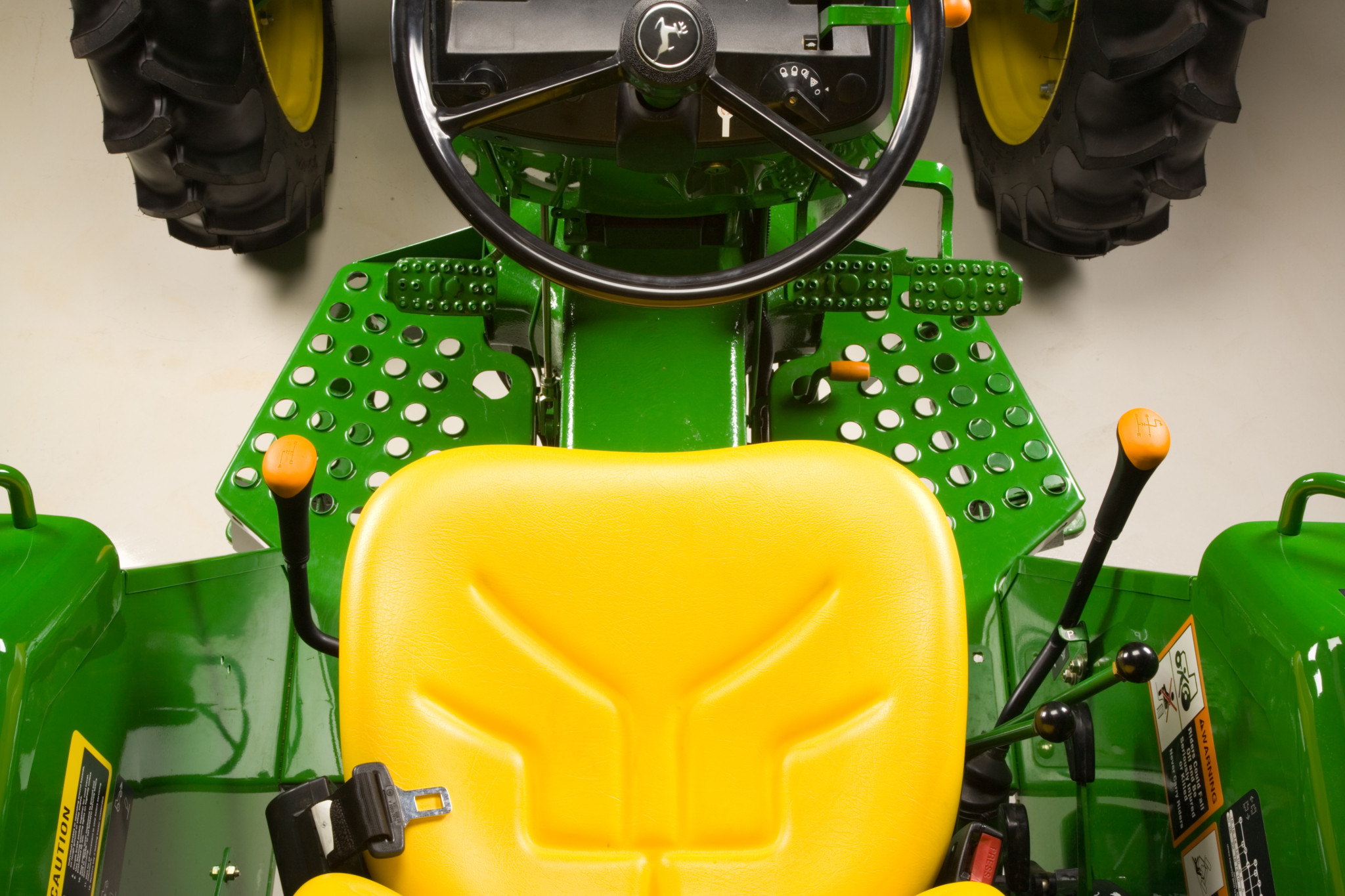Overhead studio view of 5050E Tractor seat, transmission controls, pedals, and steering wheel