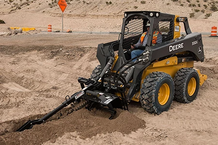 Front left view of a 300 series compact wheel loader using a TR series trencher at a dirt jobsite