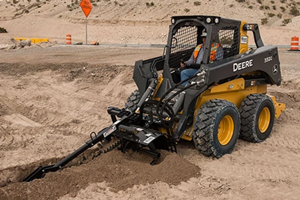 Front left view of a 300 series compact wheel loader using a TR series trencher at a dirt jobsite