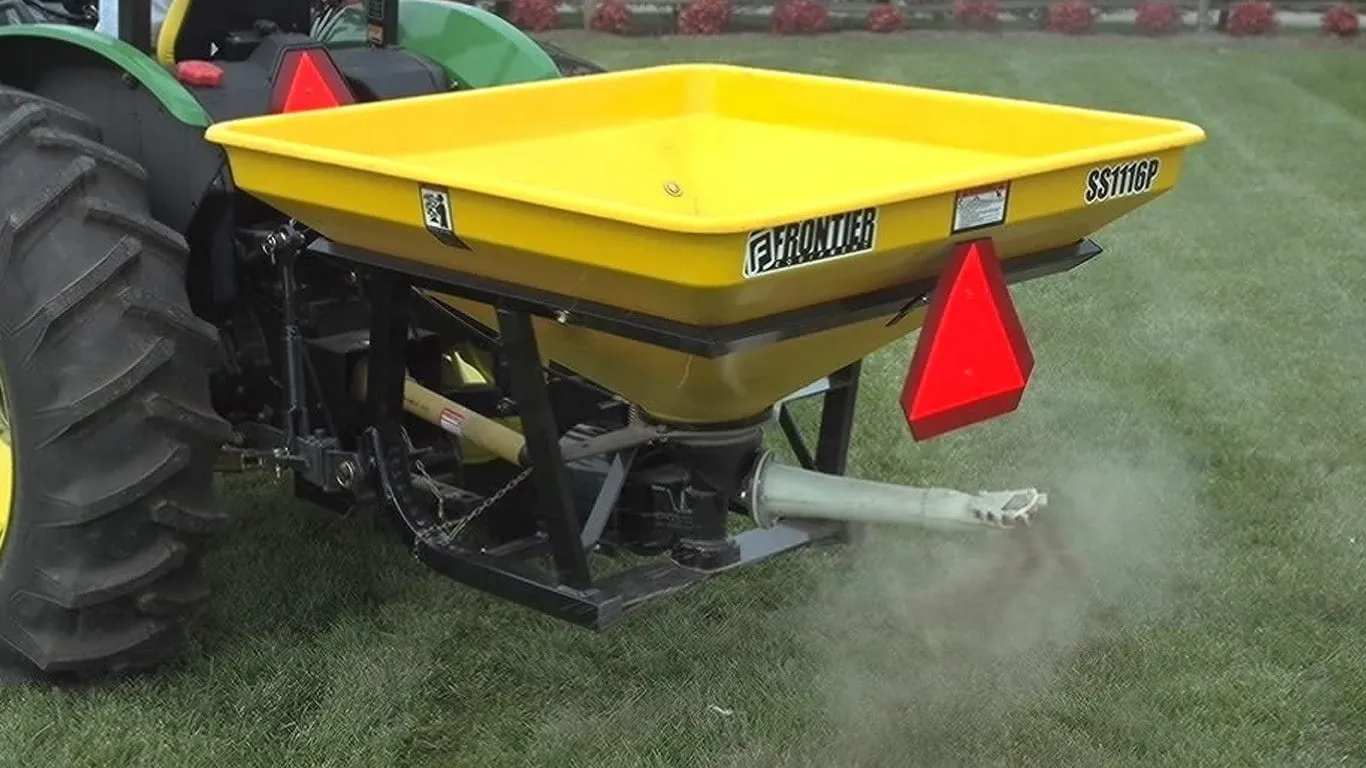 SS11P Series Pendular Spreader spreading seed behind a tractor in a field