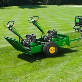 Side right view of a 22B greens mower trailer hauling two mowers across sunny grass