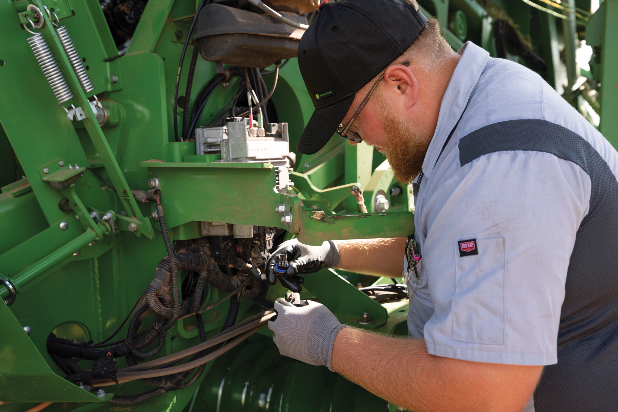 John Deere service technician working on a baler