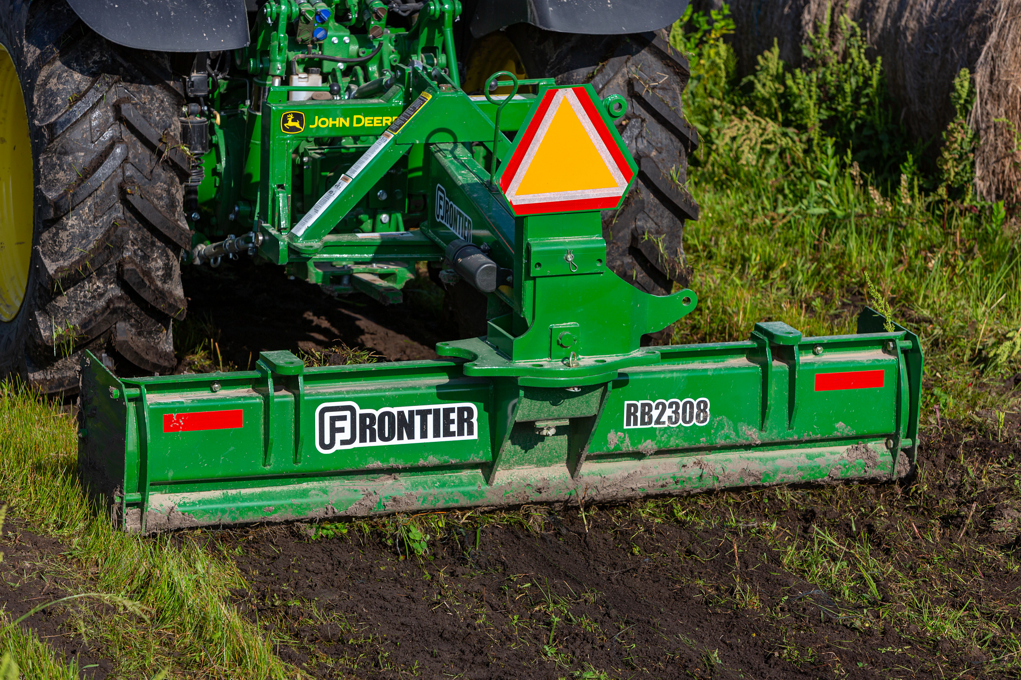 Front view of an RB2308 rear blade grading grassy dirt on the back of a 5100R tractor