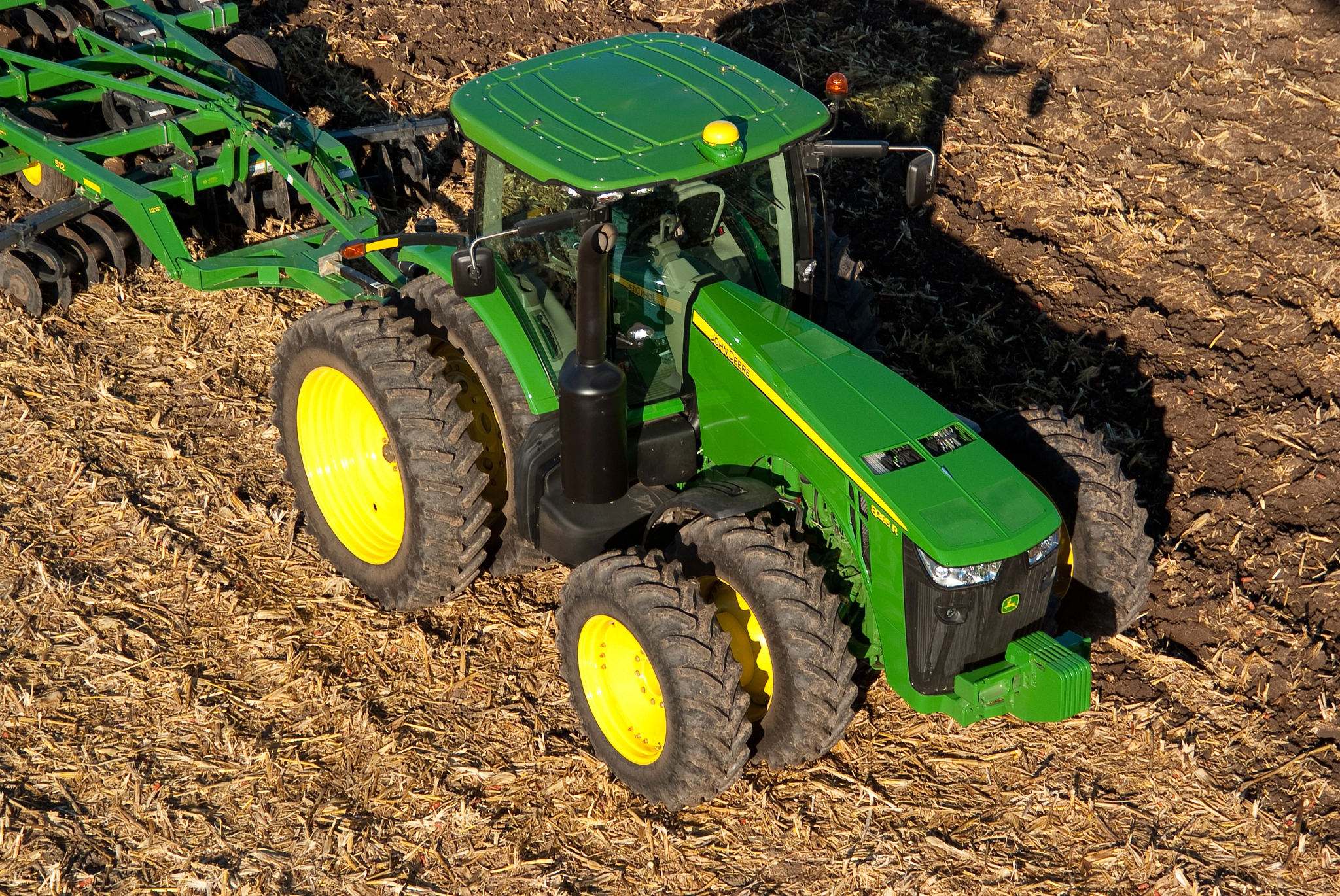 Aerial view of an 8285R tractor pulling a tillage disk ripper across a brown field