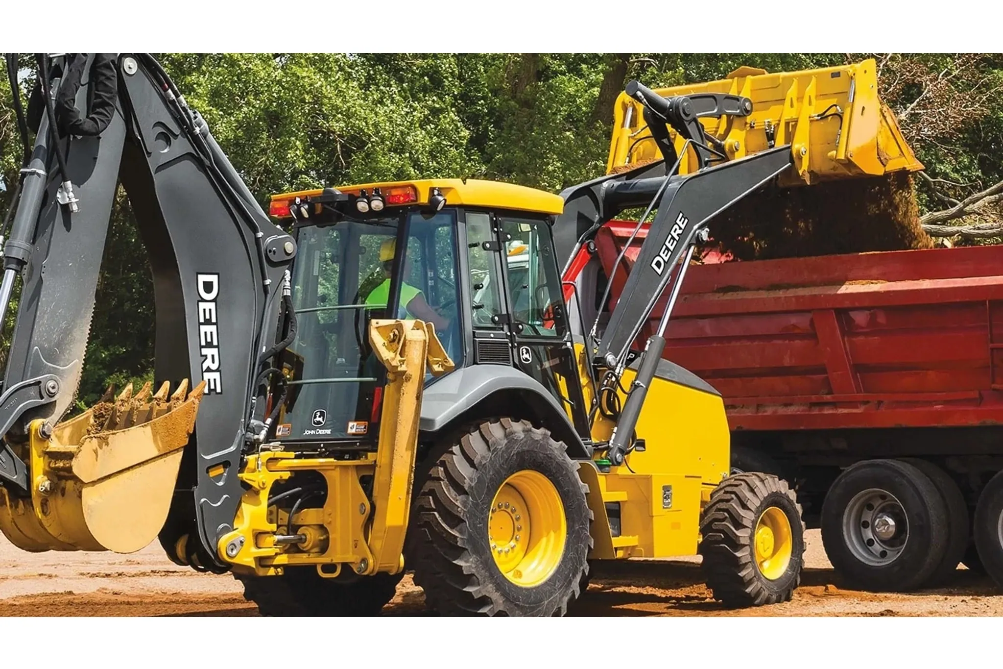 A 710 P-Tier Backhoe dumping dirt into a dump truck