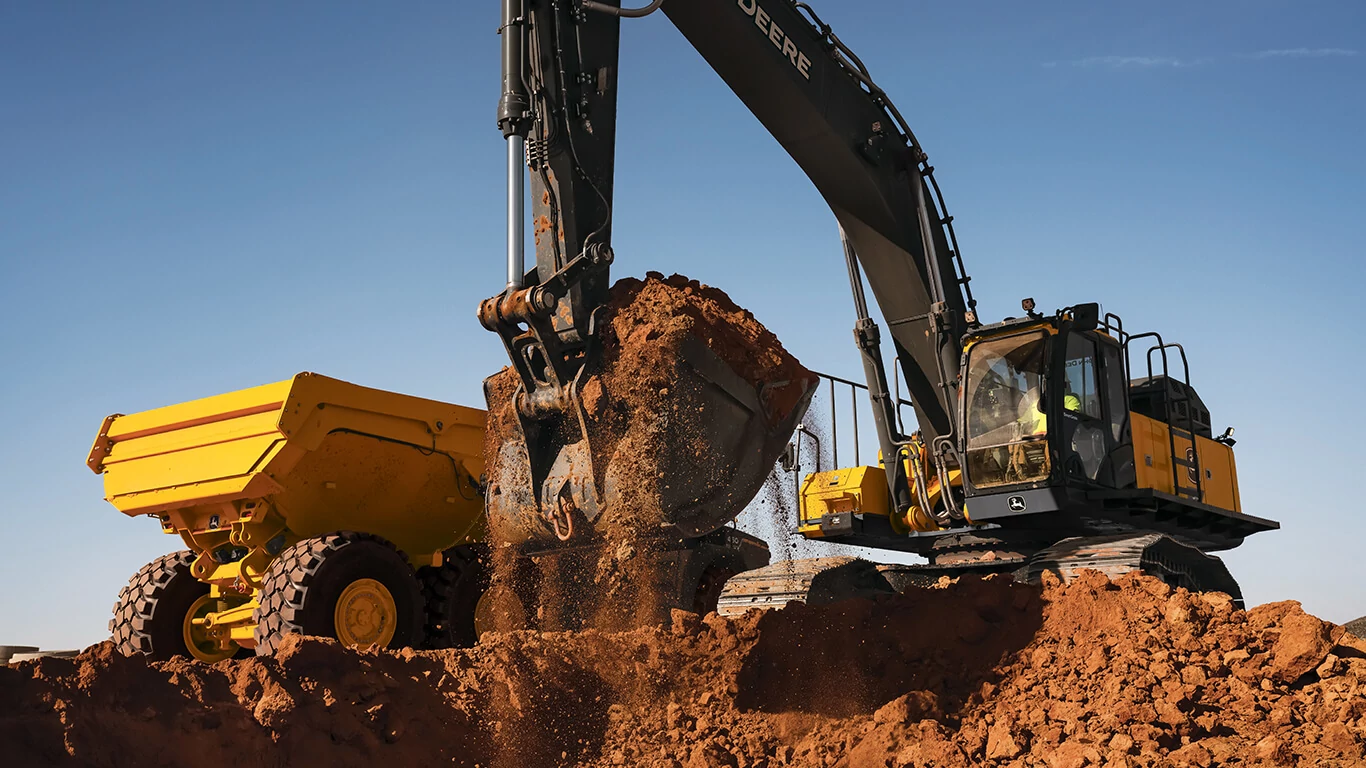 John Deere excavator moving dirt with bucket on job site.