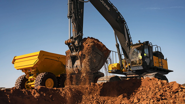 John&nbsp;Deere excavator moving dirt with bucket on job site.