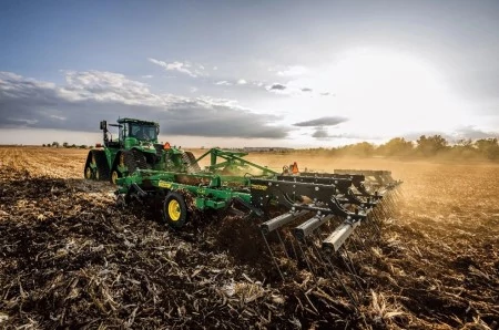 Front left view of a coulter chisel being pulled across a field by a tracked tractor
