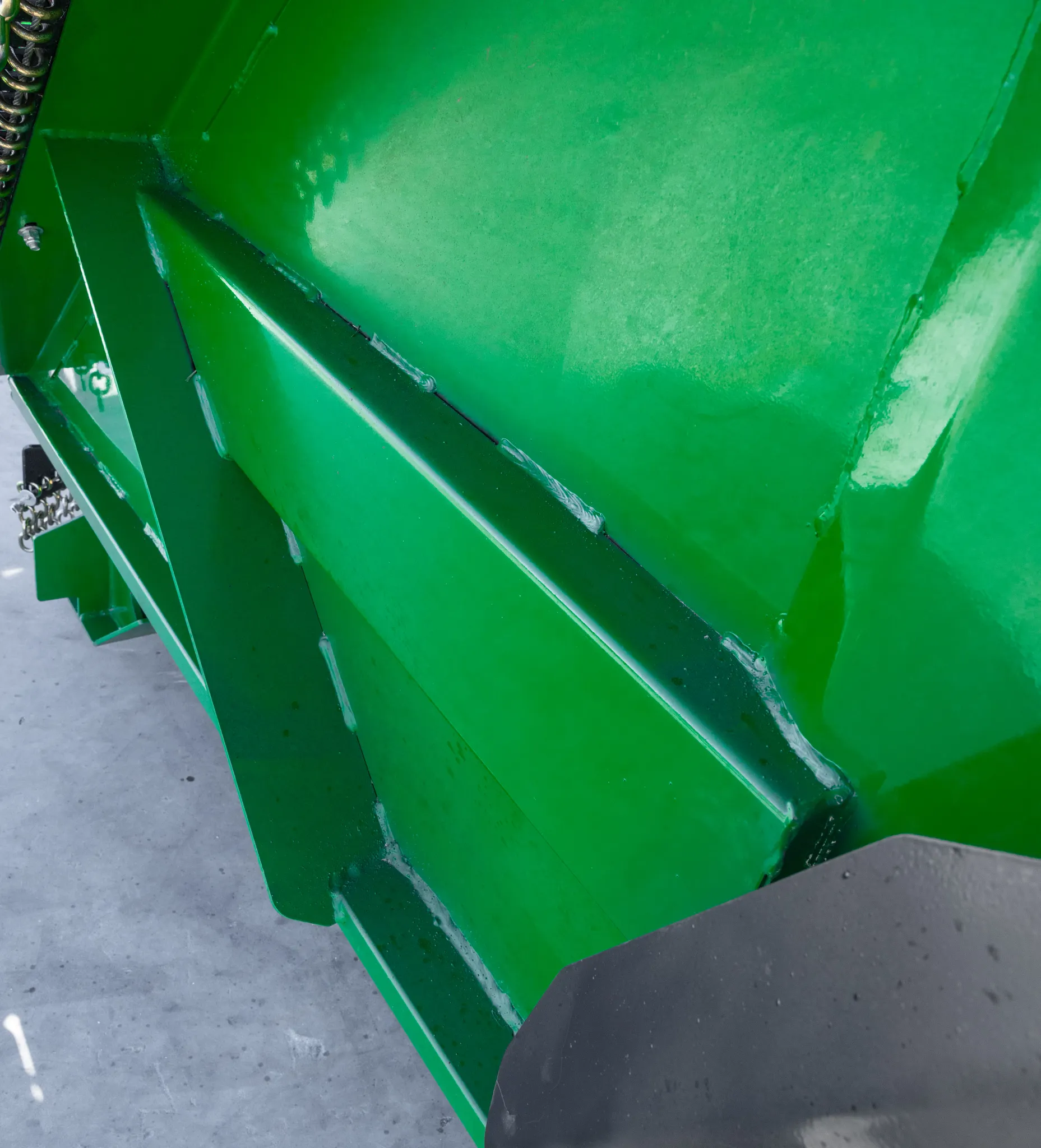 Close-up of a green steel mower deck showing reinforced welded panels and smooth painted surfaces on a rotary cutter attachment