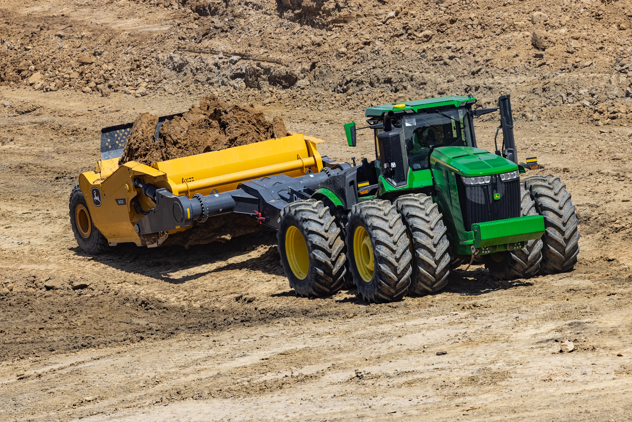 Front right view of a 9R 640 scraper special tractor pulling a loaded 3012 scraper across a dirt jobsite