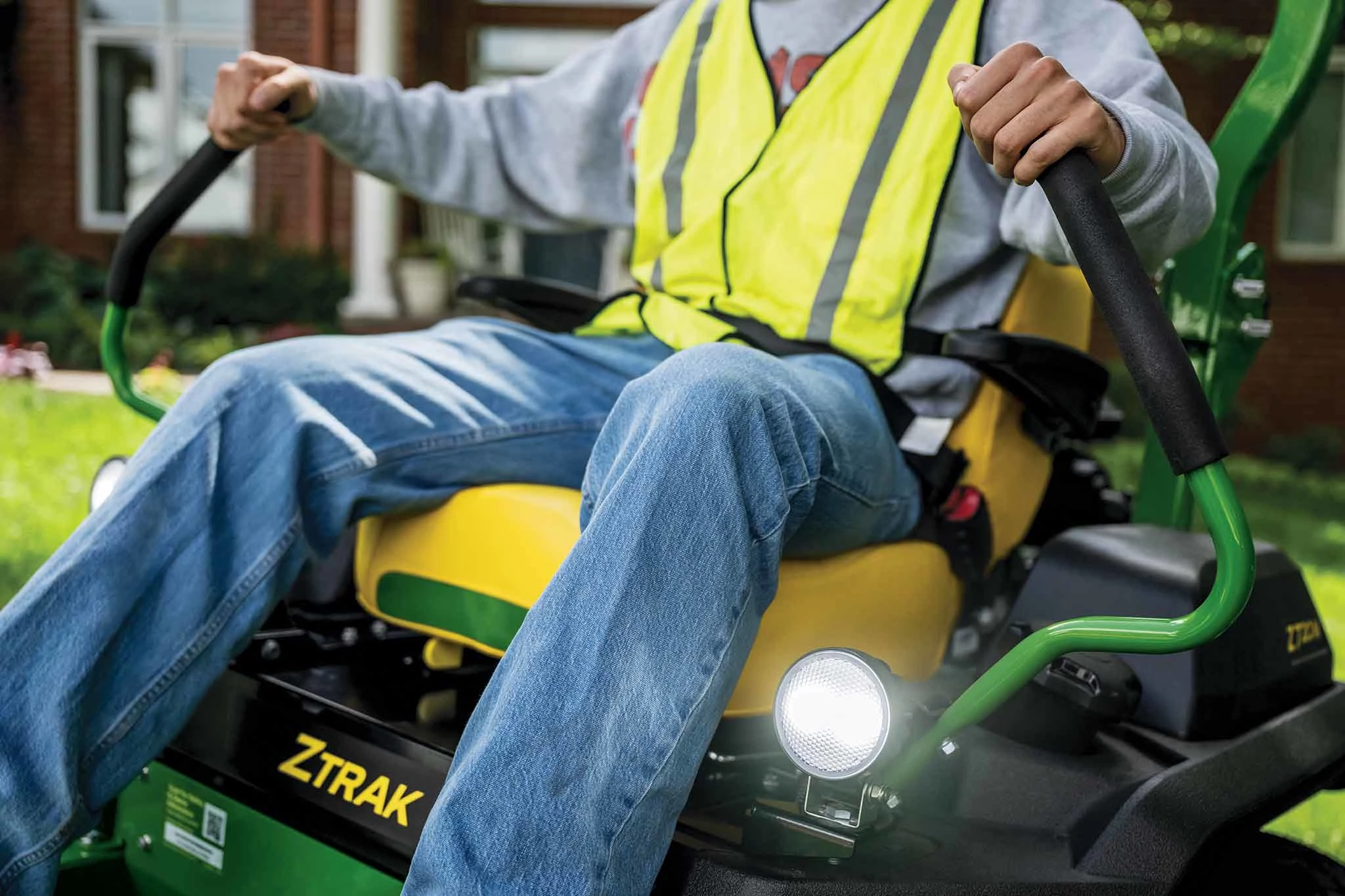 A zoomed-in shot of a landscaper operating a green Z720M zero-turn mower.