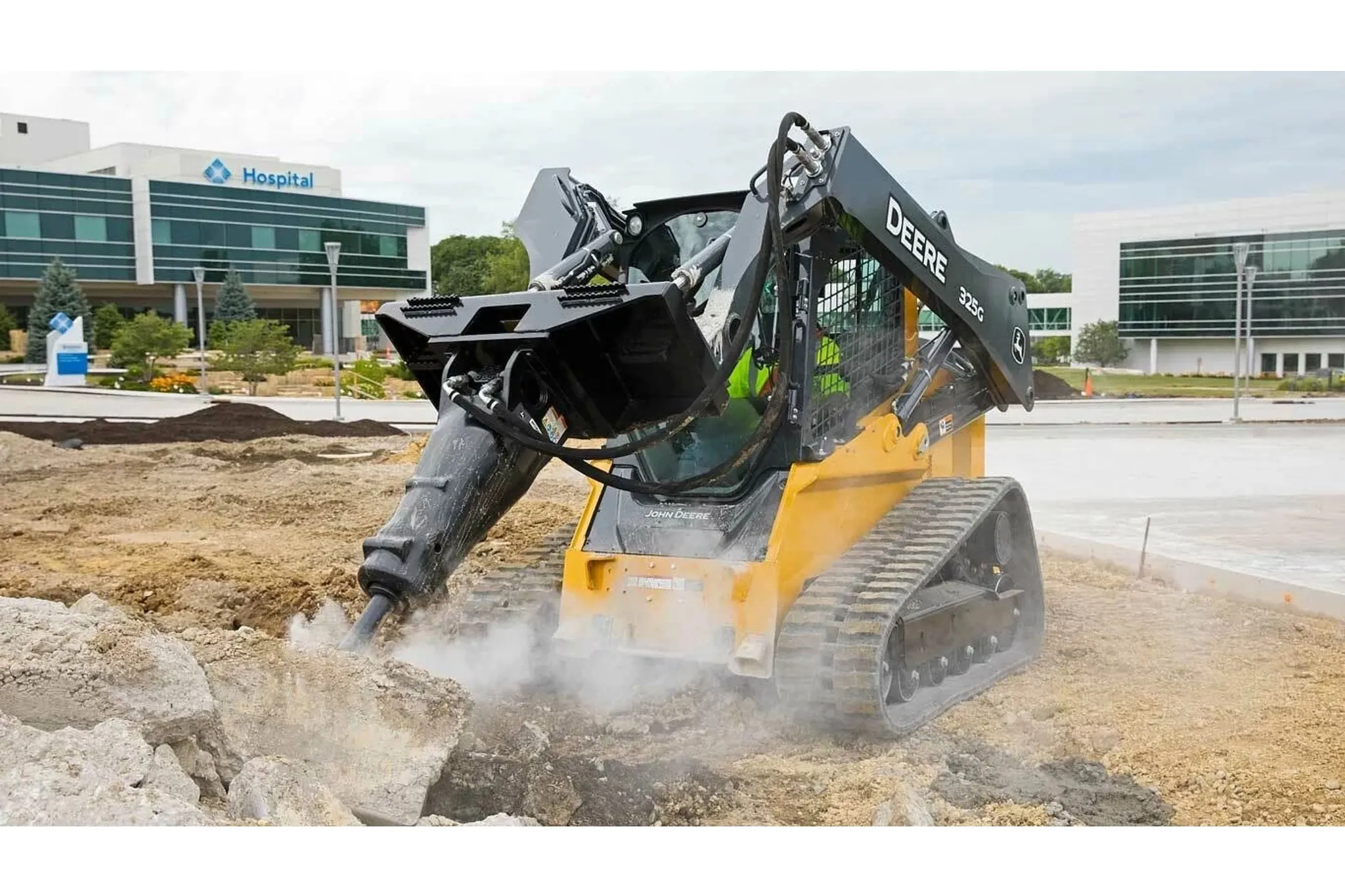 Front left view of 325G Compact Track Loader with hydraulic hammer breaking up concrete in a parking lot