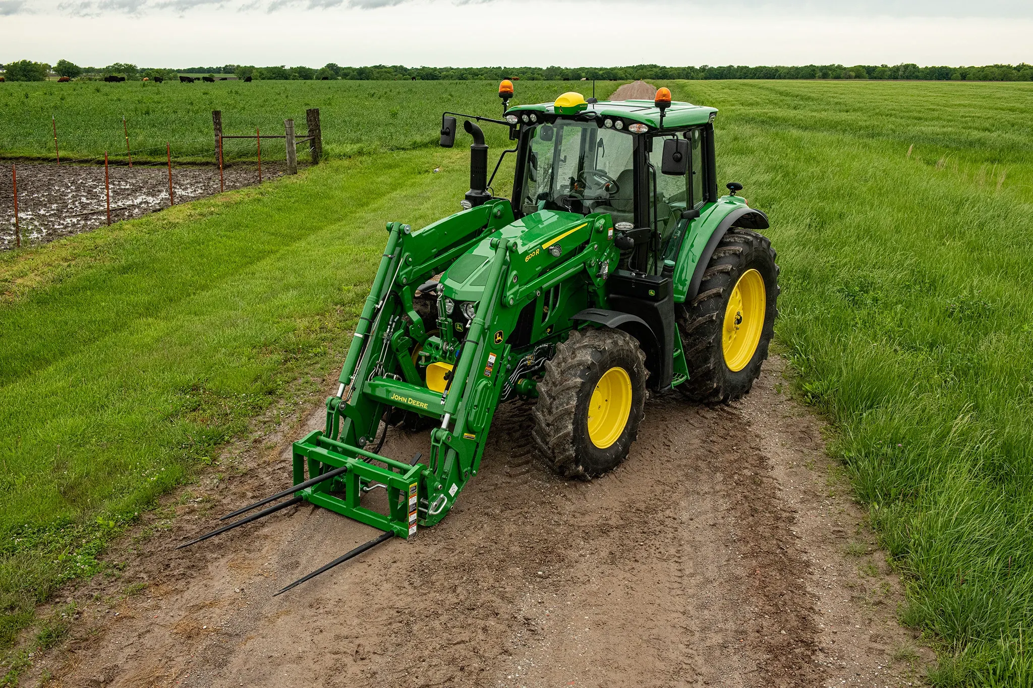Field shot of 6120M Tractor with AB12G Bale Spear on dirt path
