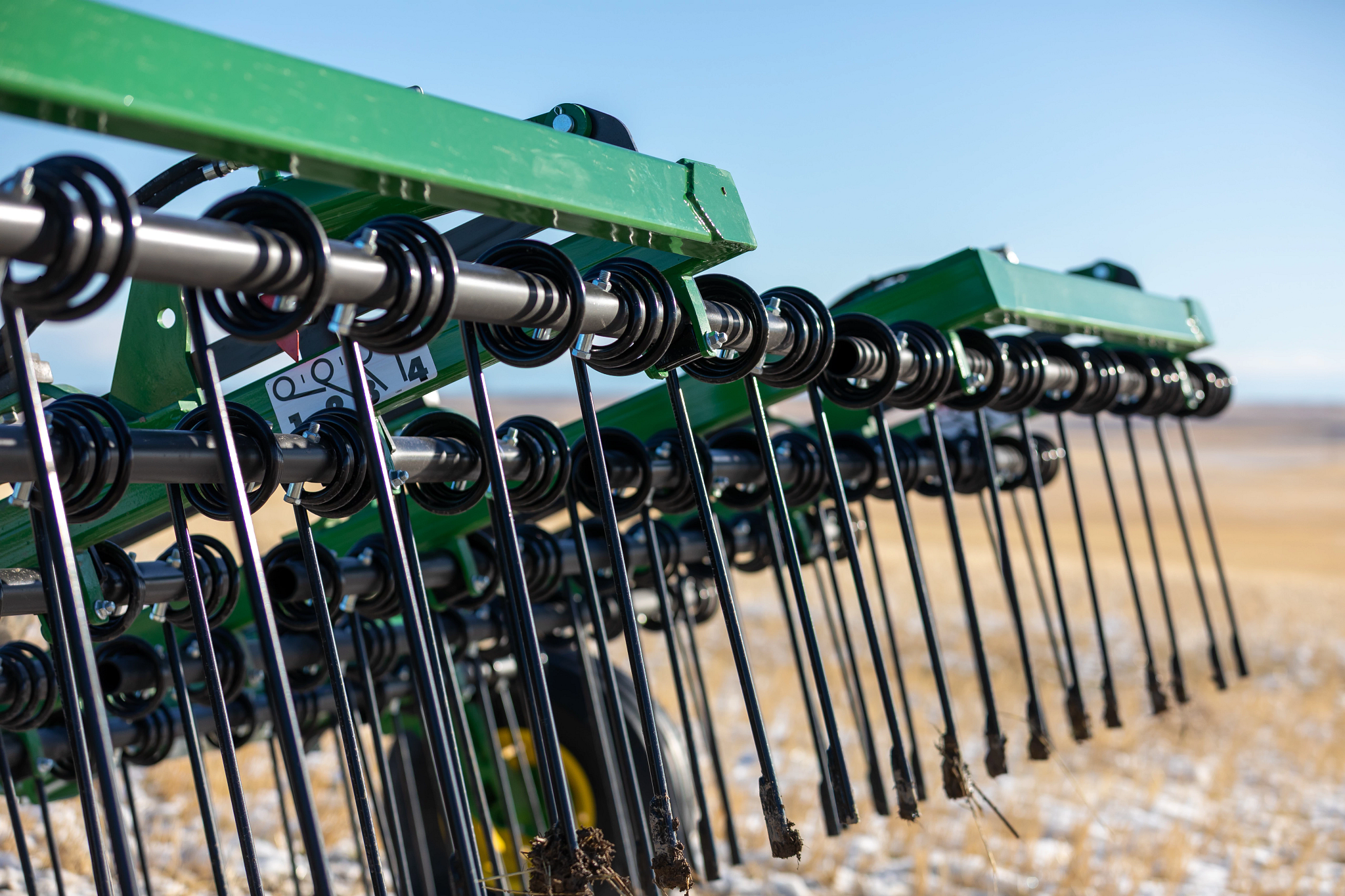 Close-up, angled shot of the tines of a five-bar HH70 Heavy Harrow in a snowy field