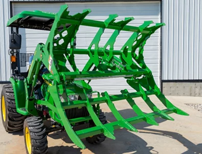 Front right view of an MG20F series mechanical grapple open wide on the front of a tractor in a shop yard
