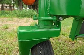 Close‑up of a green locking transport wheel assembly on a tedder positioned on grass